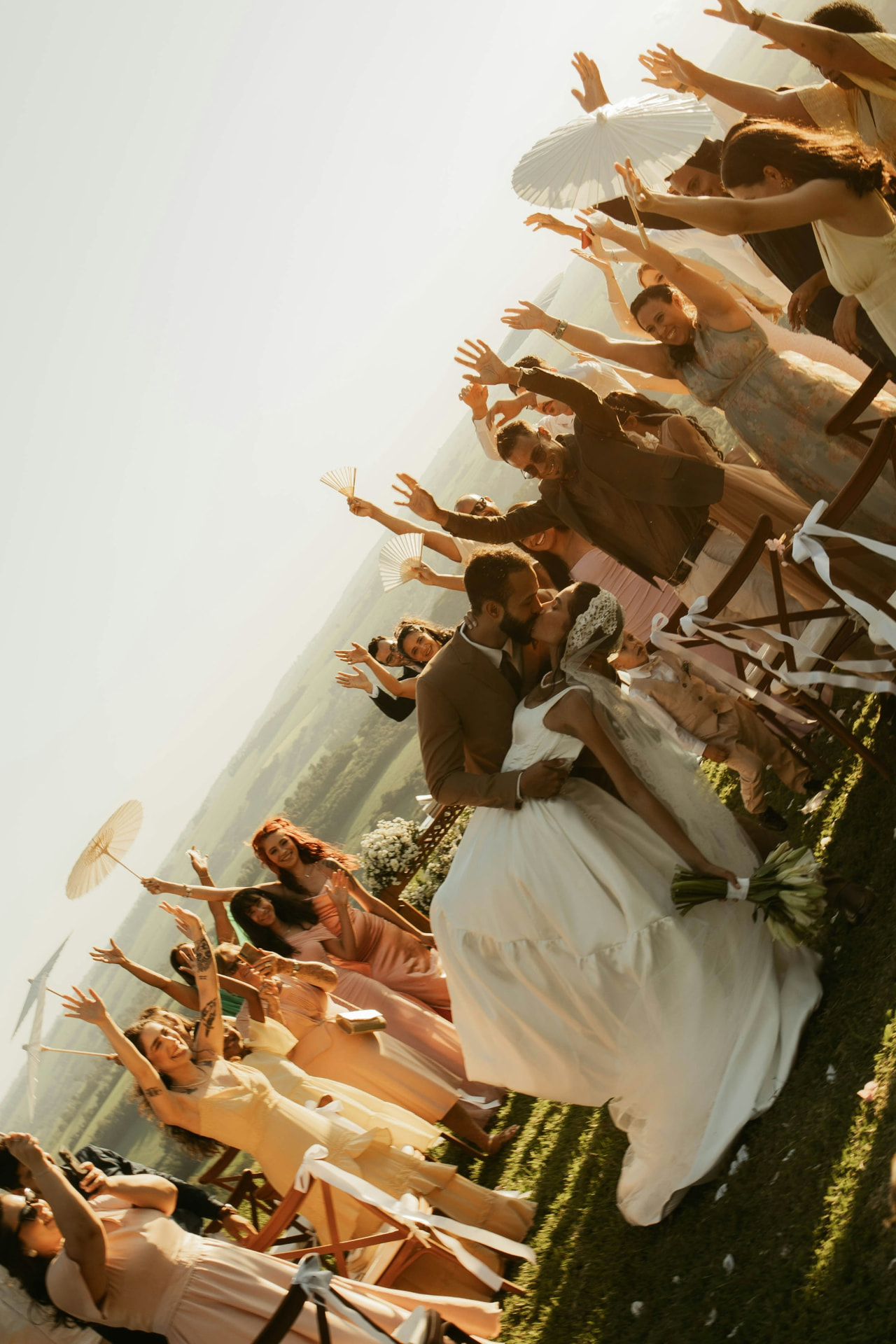 Bride and groom kissing on the aisle while guests celebrate around them